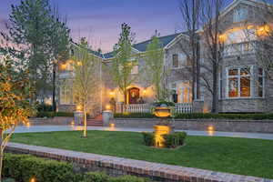 View of front of house featuring stone siding, a front yard, brick siding, and a balcony