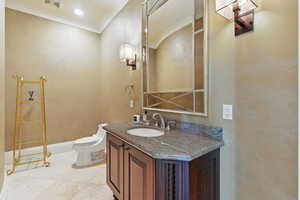 Bathroom with toilet, marble finish floor, vanity, visible vents, and crown molding