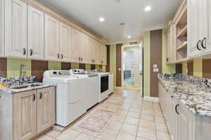 Laundry area with washing machine and dryer, recessed lighting, a sink, crown molding, and cabinet space