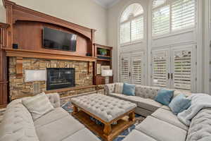 Living area with a fireplace, ornamental molding, and a towering ceiling