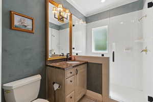 Bathroom with toilet, tile patterned floors, crown molding, a shower stall, and vanity