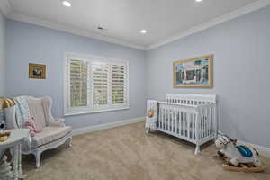 Carpeted bedroom featuring baseboards, recessed lighting, crown molding, and a crib