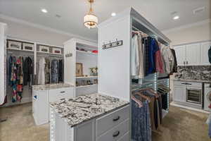 Walk in closet with light colored carpet, washer / clothes dryer, visible vents, and beverage cooler