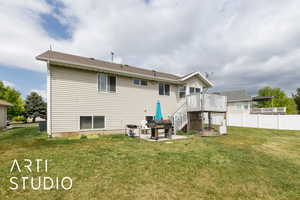Rear view of property featuring a lawn, fence, a patio area, stairway, and a wooden deck