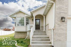 View of exterior entry featuring fence and stucco siding
