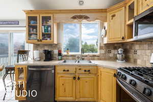 Kitchen featuring light countertops, appliances with stainless steel finishes, tasteful backsplash, and a sink