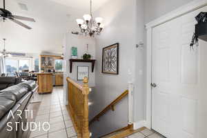Entrance foyer with a towering ceiling, ceiling fan with notable chandelier, baseboards, and light tile patterned floors