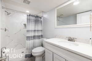 Full bathroom with toilet, vanity, visible vents, and curtained shower