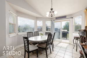 Dining space featuring lofted ceiling, baseboards, a chandelier, and light tile patterned flooring