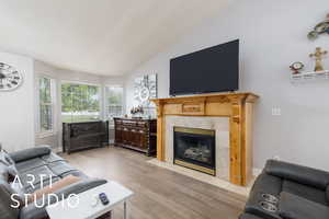 Living room with light wood-style floors, baseboards, a fireplace, and lofted ceiling