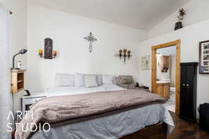 Bedroom featuring lofted ceiling, ensuite bathroom, and wood finished floors