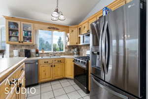 Kitchen featuring light tile patterned floors, a sink, light countertops, tasteful backsplash, and appliances with stainless steel finishes