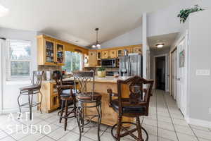 Kitchen featuring stainless steel appliances, light tile patterned floors, vaulted ceiling, light countertops, and tasteful backsplash