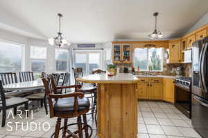 Kitchen featuring a sink, lofted ceiling, an inviting chandelier, light tile patterned floors, and appliances with stainless steel finishes
