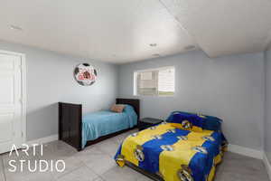 Tiled bedroom with a textured ceiling and baseboards