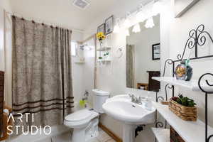 Bathroom featuring toilet, shower / bath combo, a sink, visible vents, and tile patterned flooring