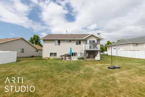 Back of house with a yard, fence, a wooden deck, and a patio