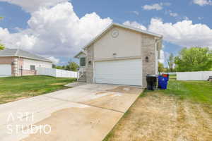 Exterior space featuring concrete driveway, a garage, fence, and a lawn