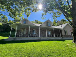 Back of property featuring stone siding, a porch, a yard, and stucco siding