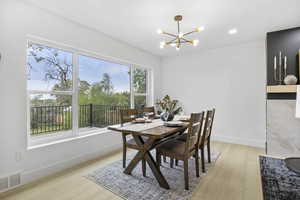 Dining room with an inviting chandelier, light wood-type flooring, visible vents, and baseboards