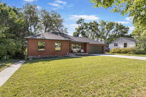 View of front of house with brick siding, concrete driveway, a front yard, and a garage