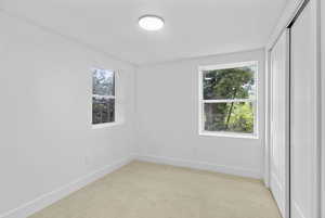 Spare room featuring light colored carpet, baseboards, and a healthy amount of sunlight