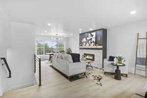 Living room featuring recessed lighting, baseboards, a high end fireplace, a chandelier, and wood finished floors