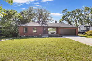 Single story home with brick siding, driveway, a garage, a front lawn, and roof with shingles