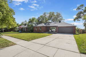 View of front of home with an attached garage, driveway, brick siding, and covered porch