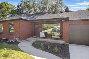 View of front of house with brick siding, a chimney, an attached garage, and a shingled roof