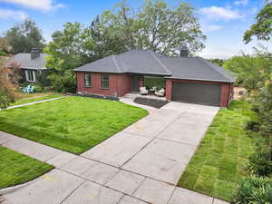 View of front facade with brick siding, concrete driveway, a front lawn, an attached garage, and roof with shingles