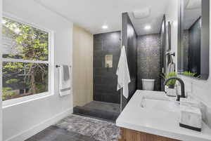 Bathroom with vanity, a walk in shower, baseboards, and tile patterned floors