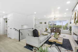 Living area with recessed lighting, baseboards, an inviting chandelier, a tile fireplace, and light wood-type flooring