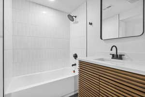 Bathroom with vanity, shower / tub combination, and visible vents