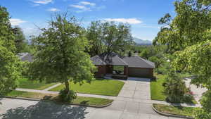View of front of property featuring an attached garage, a front yard, concrete driveway, roof with shingles, and a mountain view