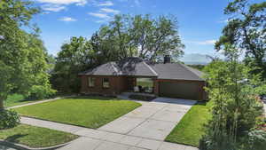 View of front of home with a front lawn, a garage, brick siding, and concrete driveway