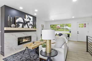 Living room featuring light wood-type flooring, a high end fireplace, and recessed lighting