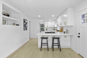 Kitchen with baseboards, light wood finished floors, light countertops, and white cabinets