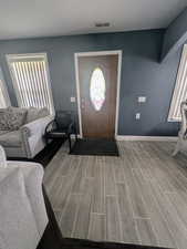 Foyer entrance featuring baseboards, visible vents, and wood finished floors