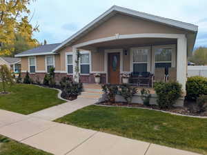 View of front of property with covered porch, brick siding, and stucco siding