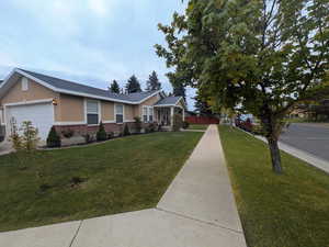 View of front facade featuring stucco siding, an attached garage, a front lawn, and brick siding