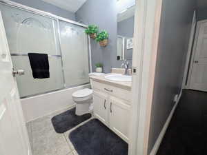 Full bath with vanity, toilet, shower / bath combination with glass door, and tile patterned floors