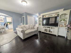Living area featuring arched walkways, baseboards, an inviting chandelier, and wood-type flooring