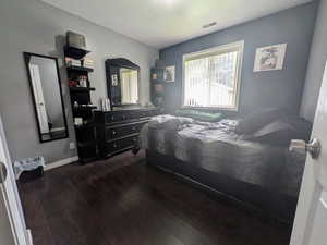 Bedroom featuring baseboards, visible vents, and dark wood finished floors