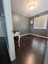 Interior space with baseboards, wood-type flooring, visible vents, and a textured ceiling