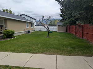 View of yard with a fenced backyard, an outdoor structure, a storage unit, and central AC