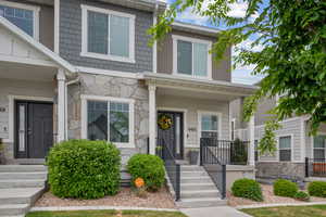 Townhome / multi-family property featuring stone siding and a porch