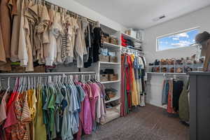 Walk in closet featuring visible vents and carpet floors