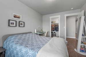 Bedroom with carpet flooring, a closet, baseboards, and a walk in closet