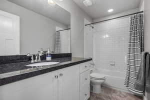 Bathroom featuring vanity, shower / tub combo with curtain, and toilet